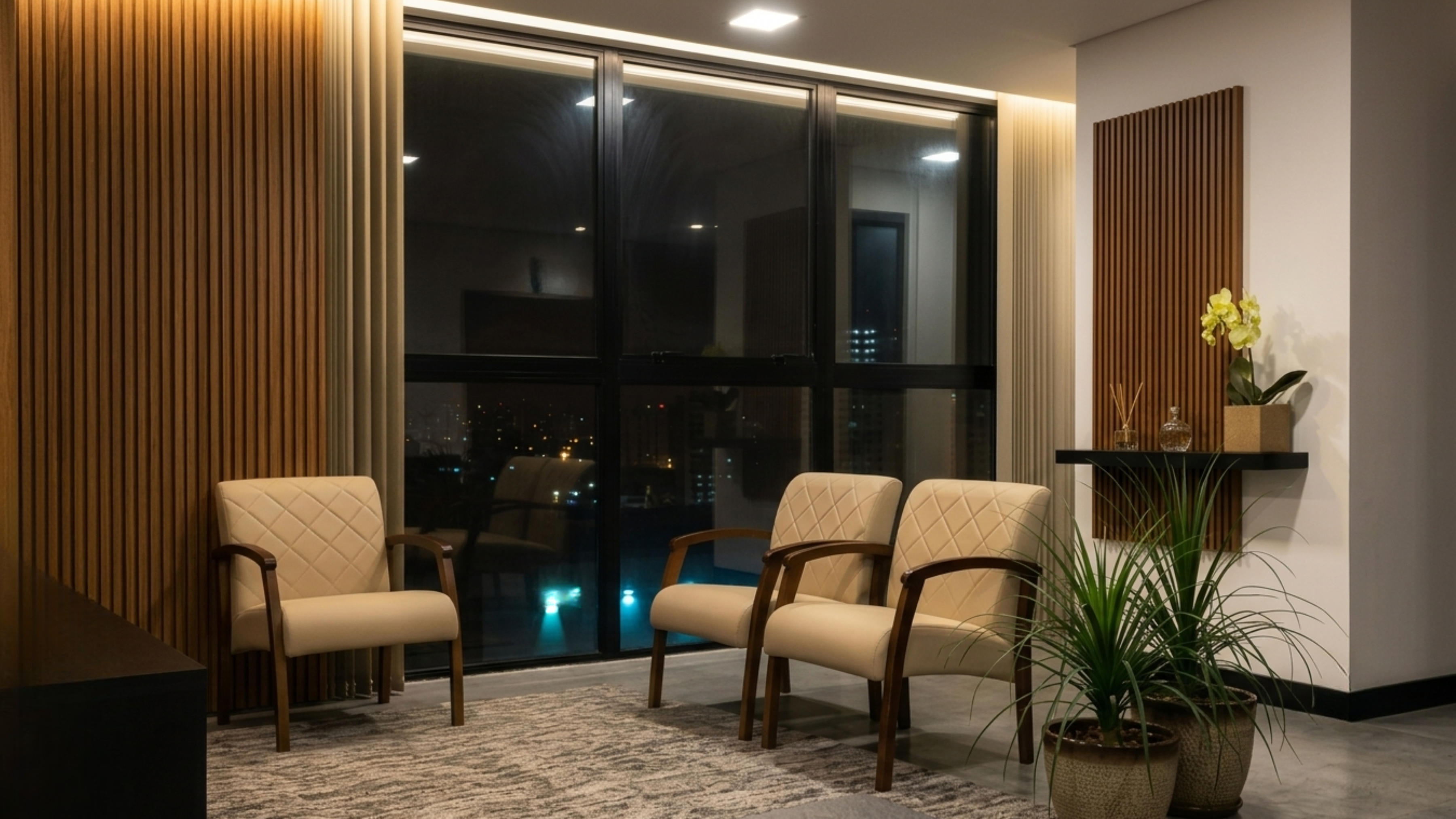 Espaço de espera com poltronas e vista noturna da cidade